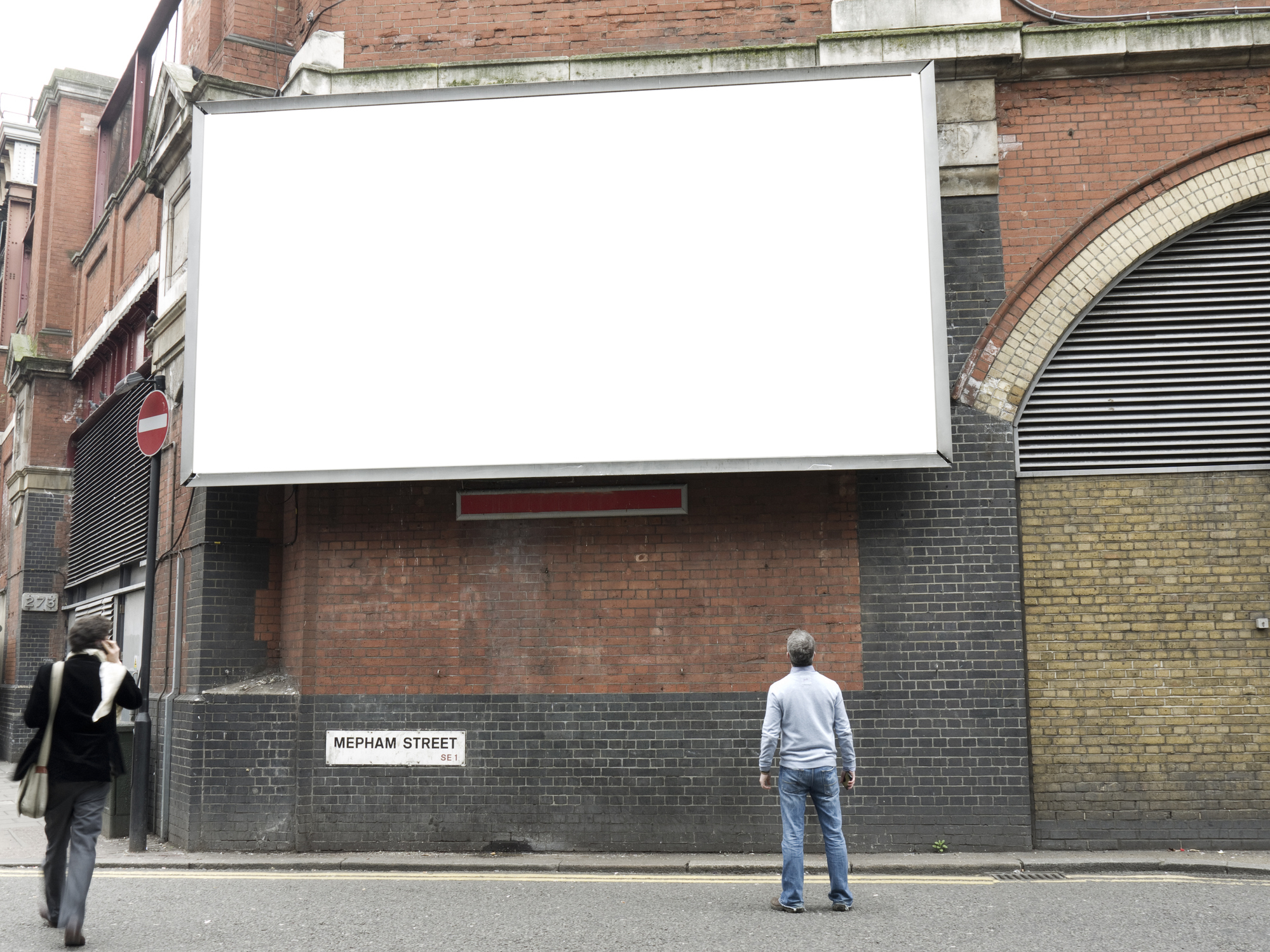 Man standing in front of a large blank billboard on a city street