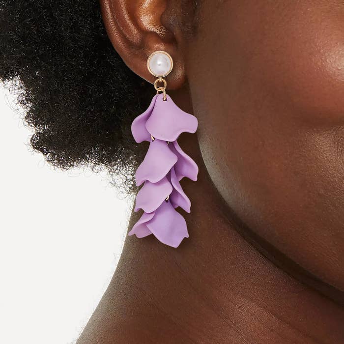 Model wearing a tiered purple earring with a pearl stud