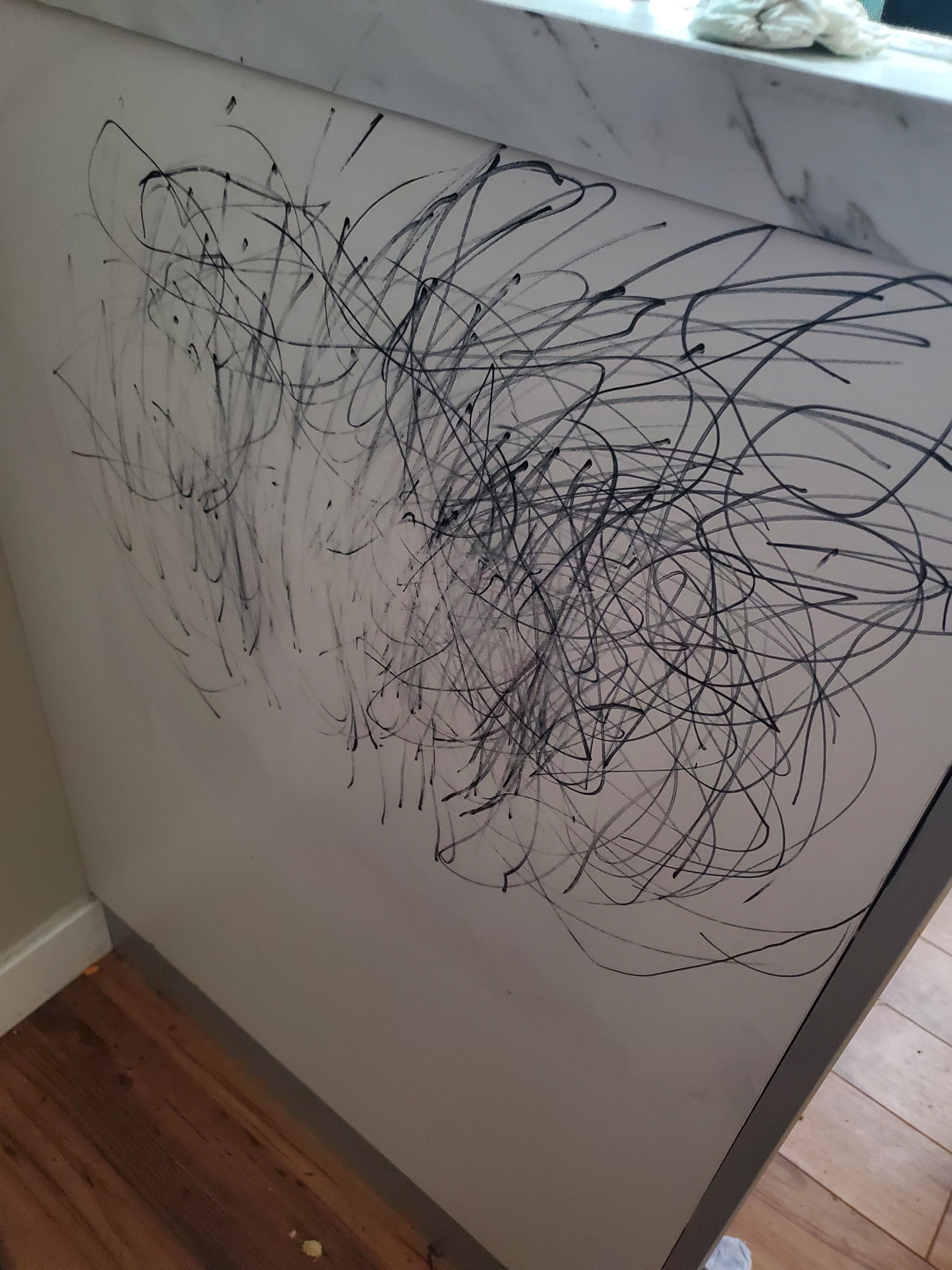Scratches and scribbles cover a white surface, implying a child&#x27;s drawing or accidental marks