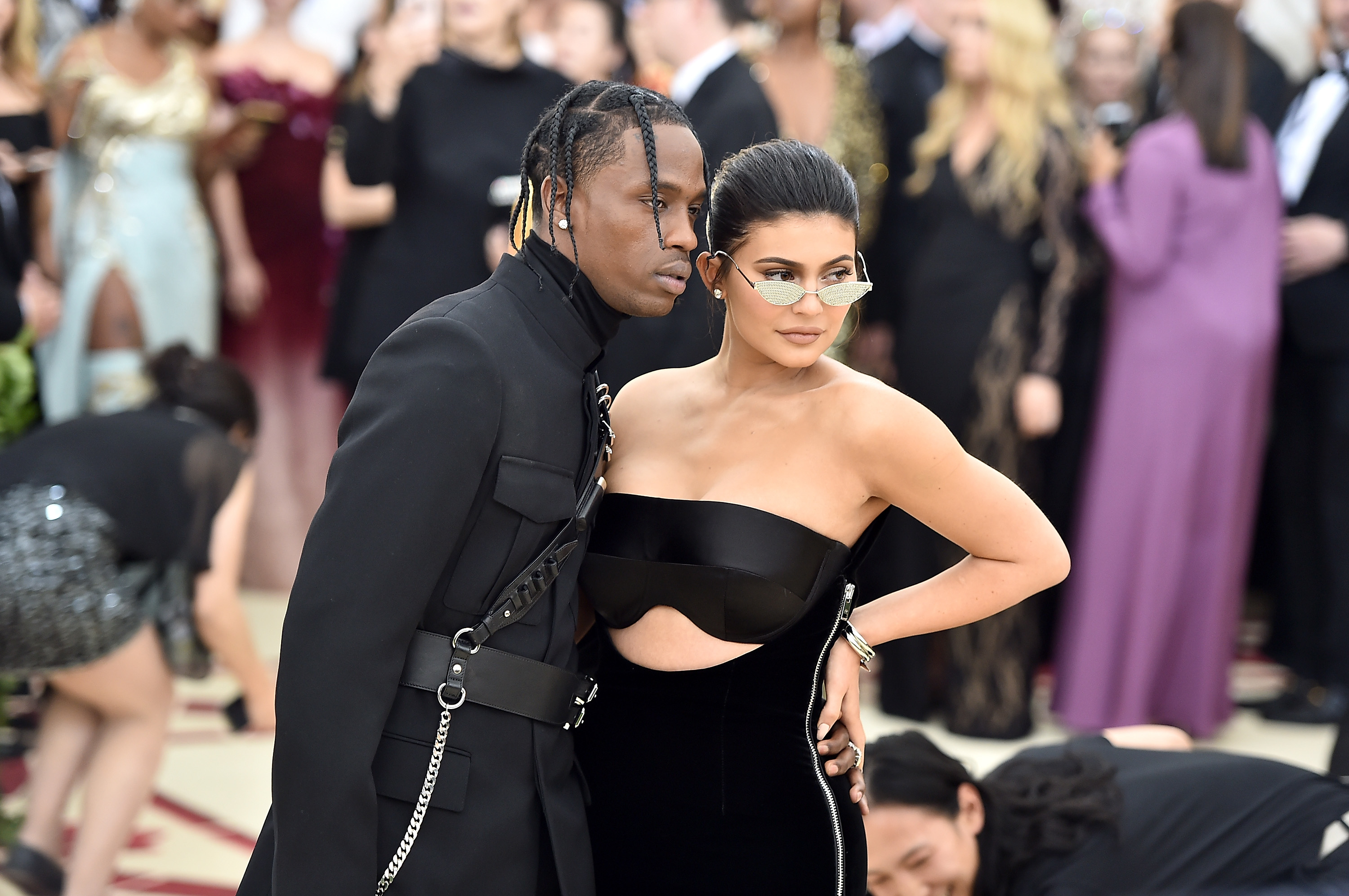 Travis Scott and Kylie Jenner pose together; he in a suit, she in a structured strapless gown