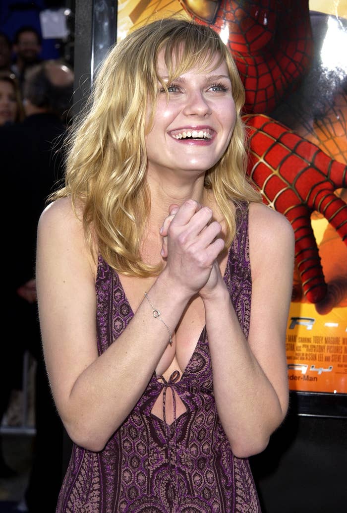 closeup of kirsten at the spider-man premiere smiling big with her hands clasped in front of her