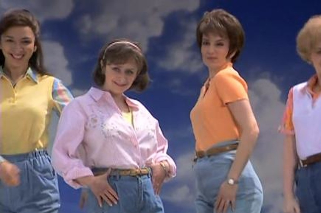 Four women in vintage attire with high-waisted jeans and casual tops, posing confidently