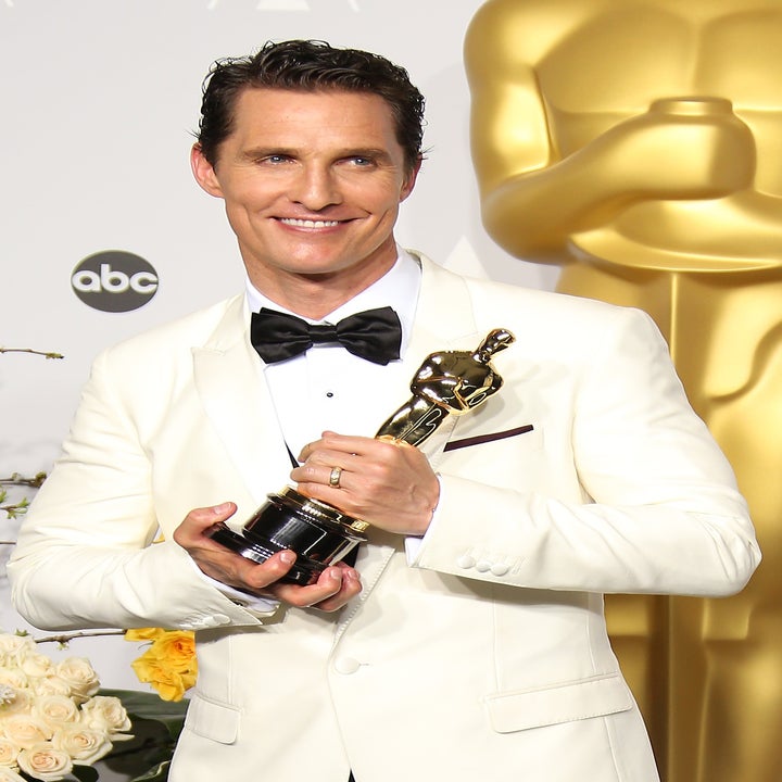 Matthew mcconaughey in a white tuxedo holding an Oscar statue at an awards show