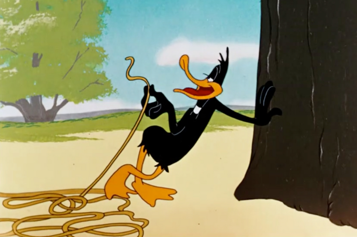 Animated character Daffy Duck leaning against a tree with a rope in hand, in a classic Looney Tunes scene