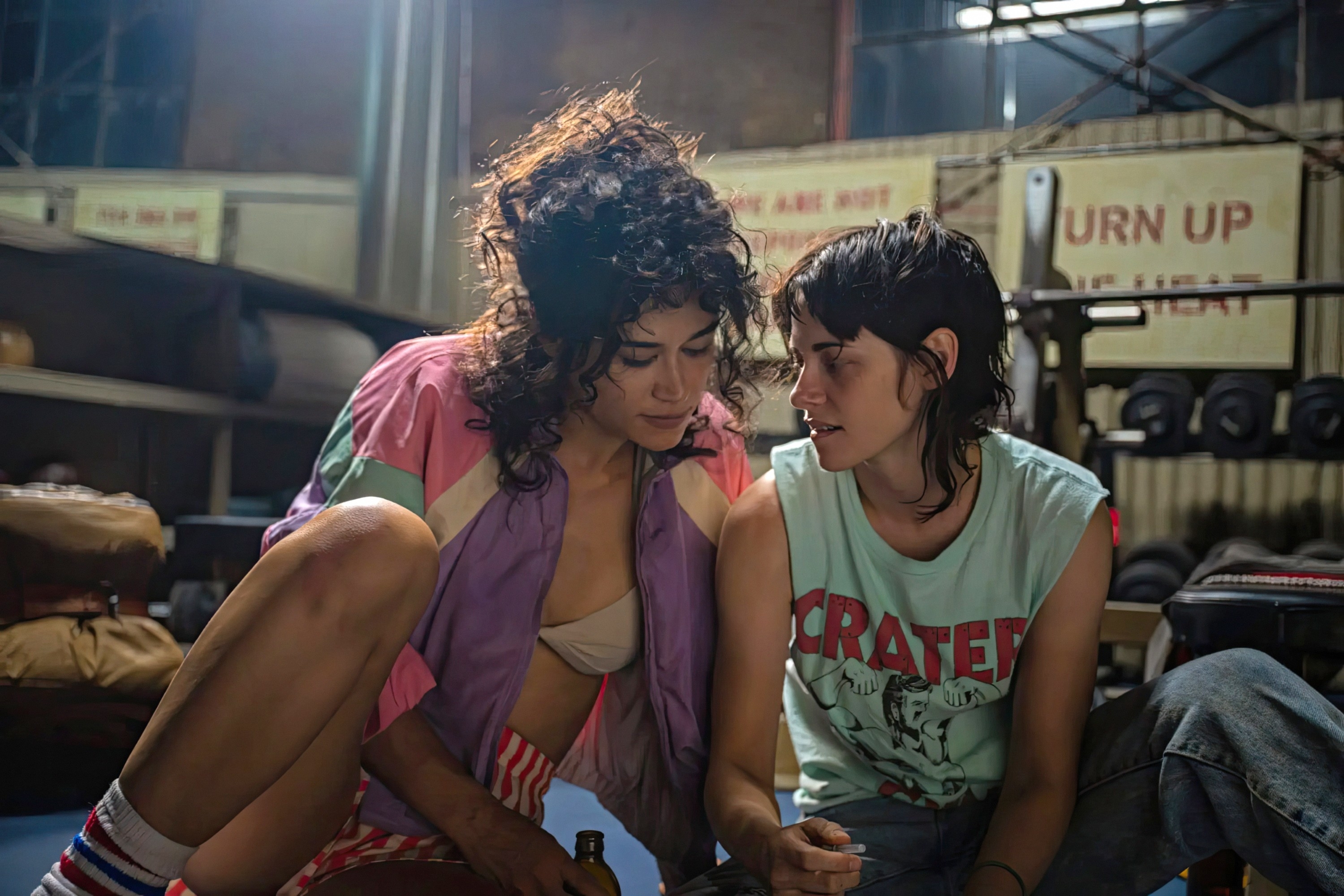 Lou and Katy&#x27;s character sitting close together on a gym floor in a scene from a production