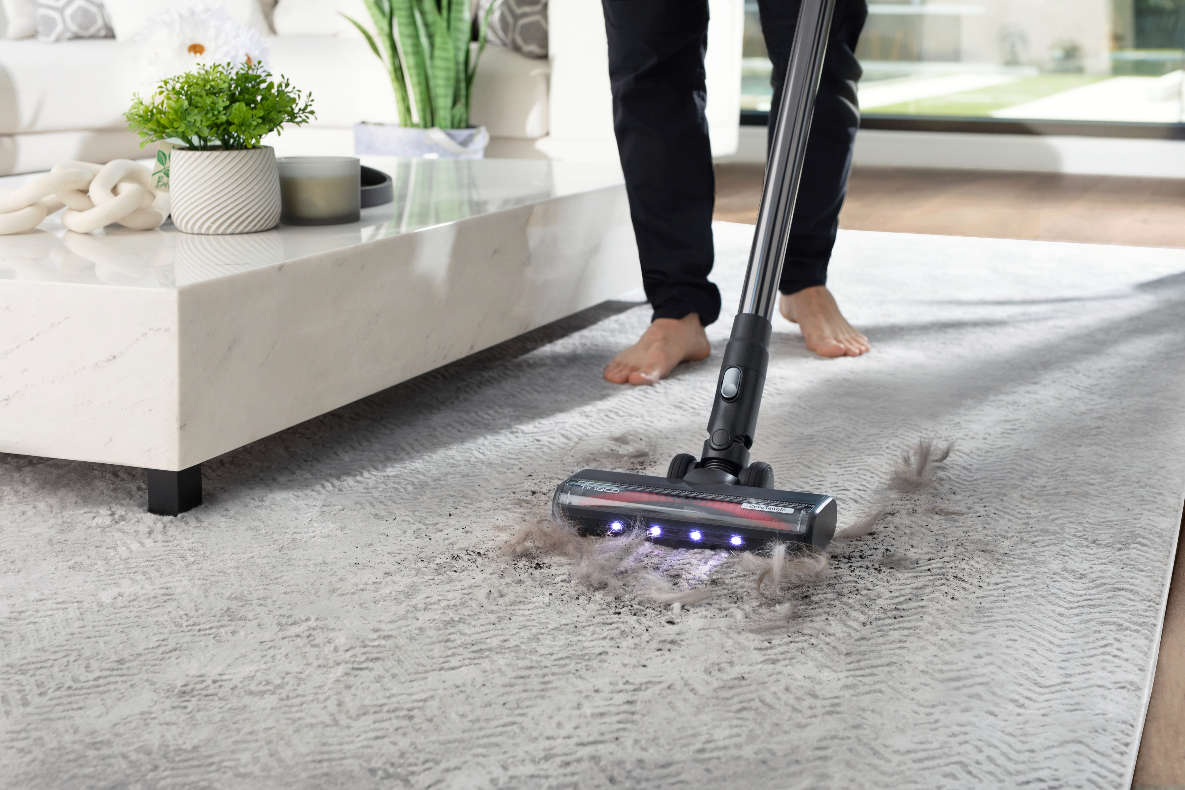 Person vacuuming a carpet showing a clean path where dust has been removed