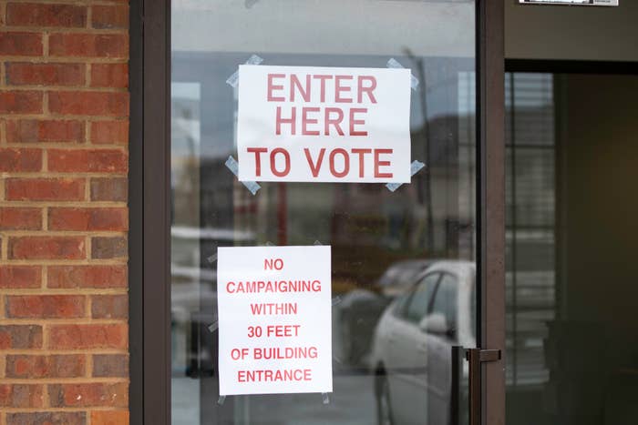 A door with two signs reading &quot;ENTER HERE TO VOTE&quot; and &quot;NO CAMPAIGNING WITHIN 30 FEET OF BUILDING ENTRANCE.&quot;