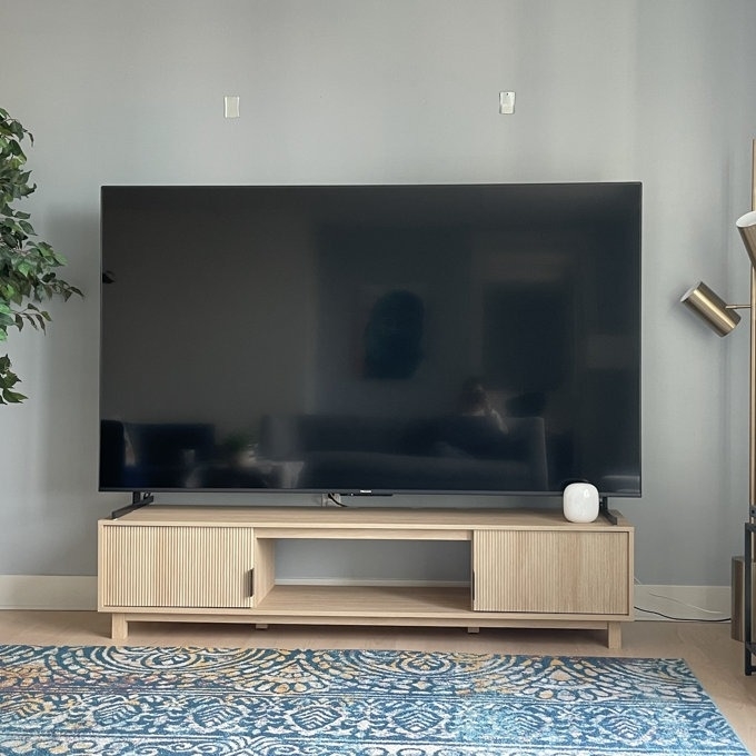Large flat-screen TV on a wooden media console with decorative items, in a living room setting