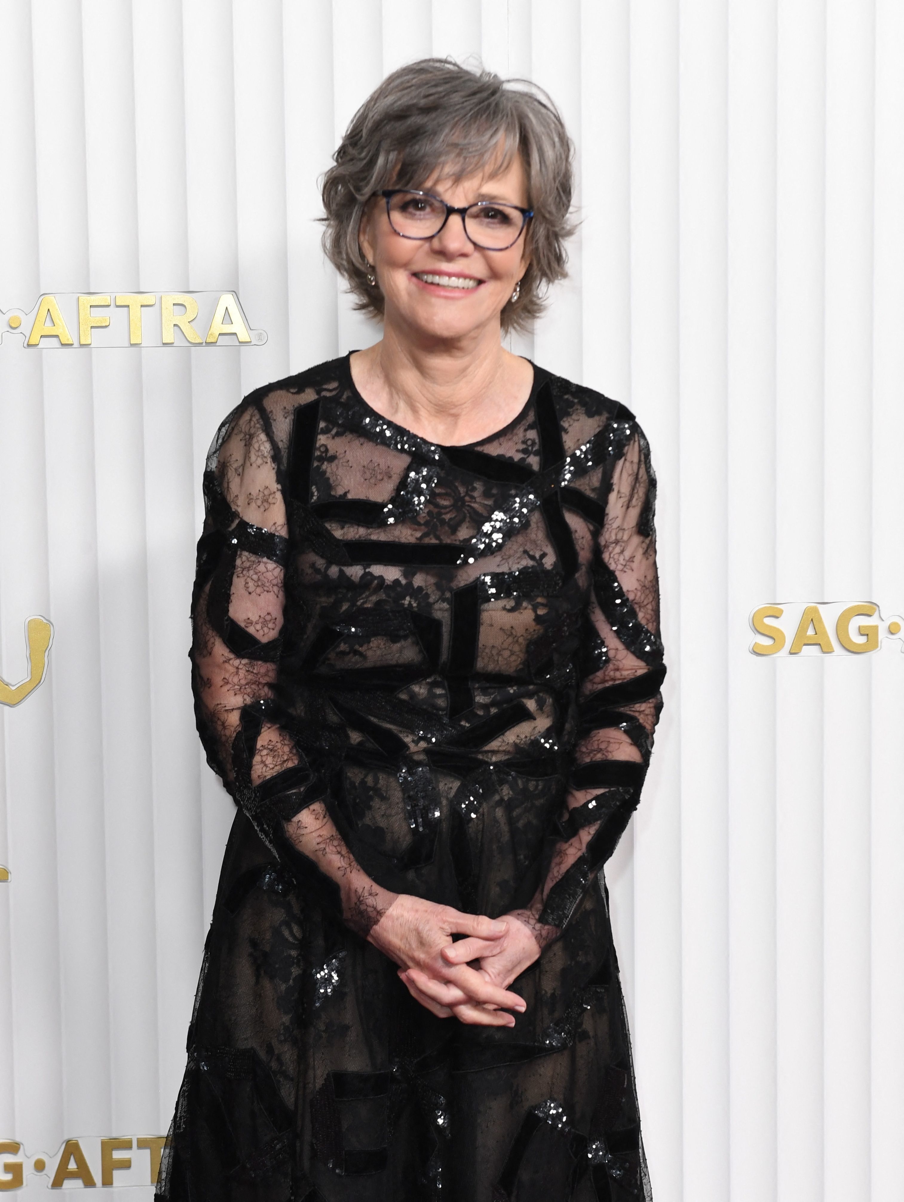A person in an elegant black lace dress with sequin details posing at the SAG-AFTRA event