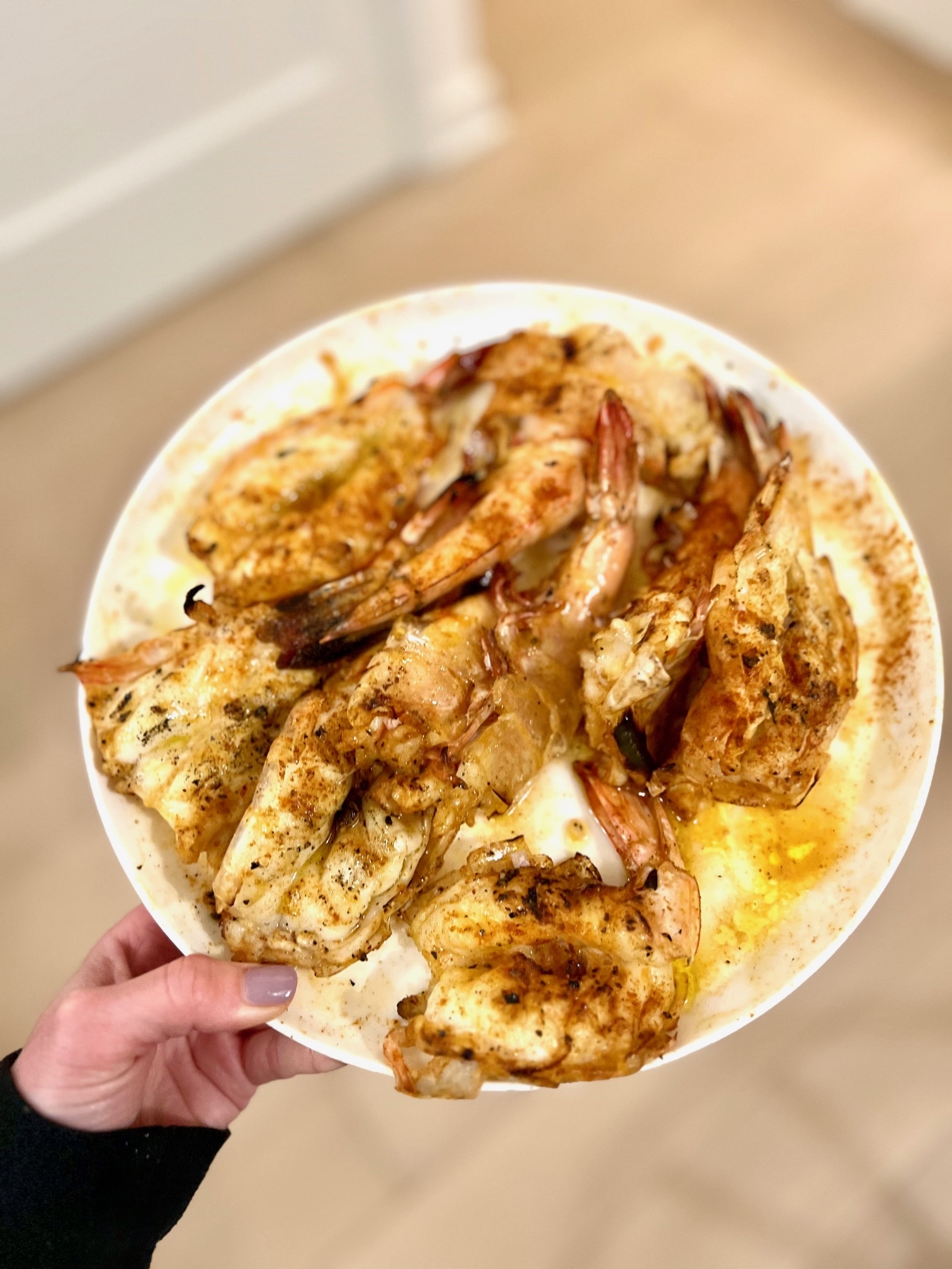 Person holding a plate of grilled prawns