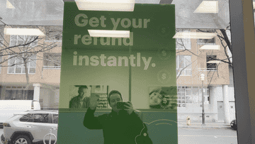 Une publicité pour des remboursements d'impôts instantanés avec le reflet masqué d'une personne en train de prendre la photo.