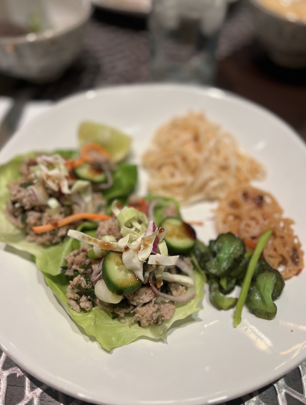 Lettuce wraps filled with meat and vegetables, side of noodles and spinach