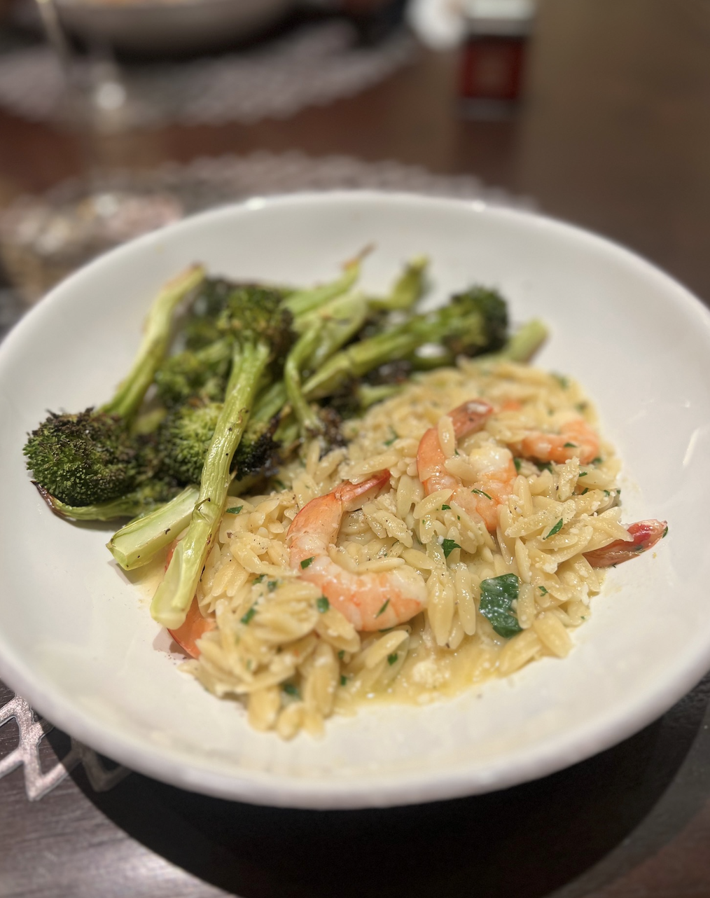 Plate of shrimp orzo with broccoli served on a table
