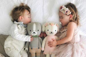 two toddlers cuddle with plush toys of dogs
