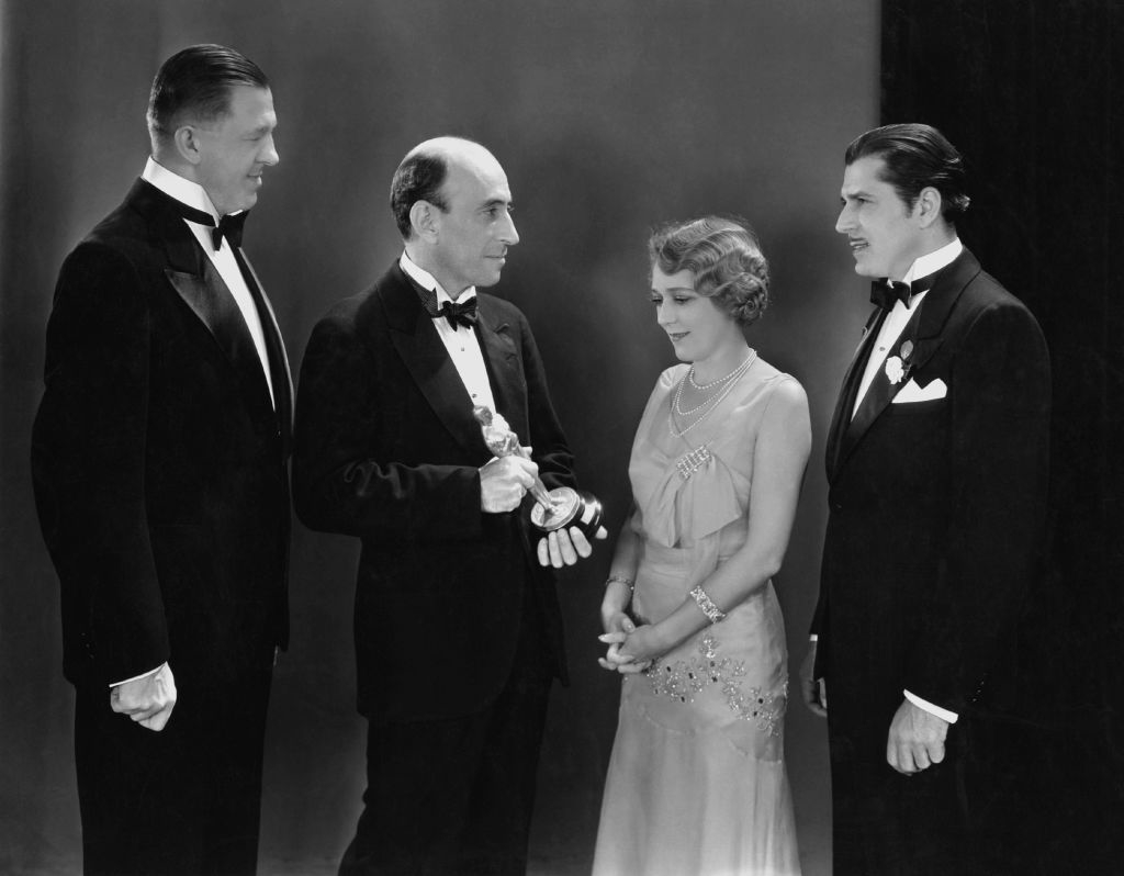 Three men in tuxes present Mary with her Oscar