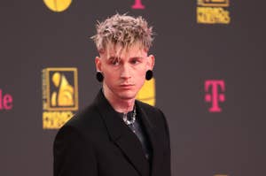 MGK in a black suit with posing on the event backdrop
