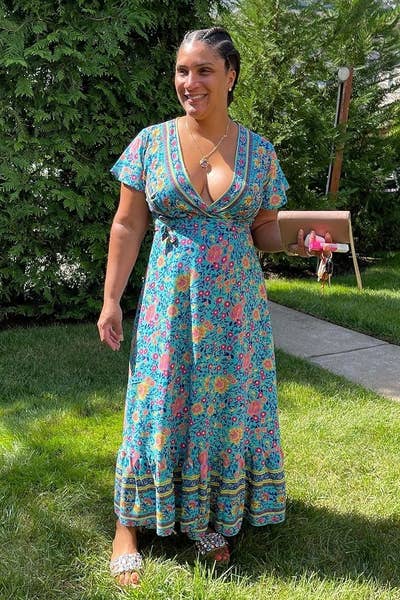 a reviewer in a blue floral print dress standing in a garden
