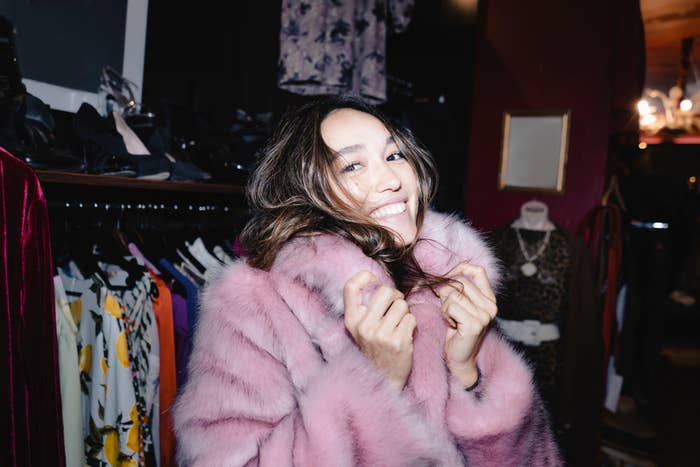Woman in a boutique wearing a faux fur coat, smiling with joy