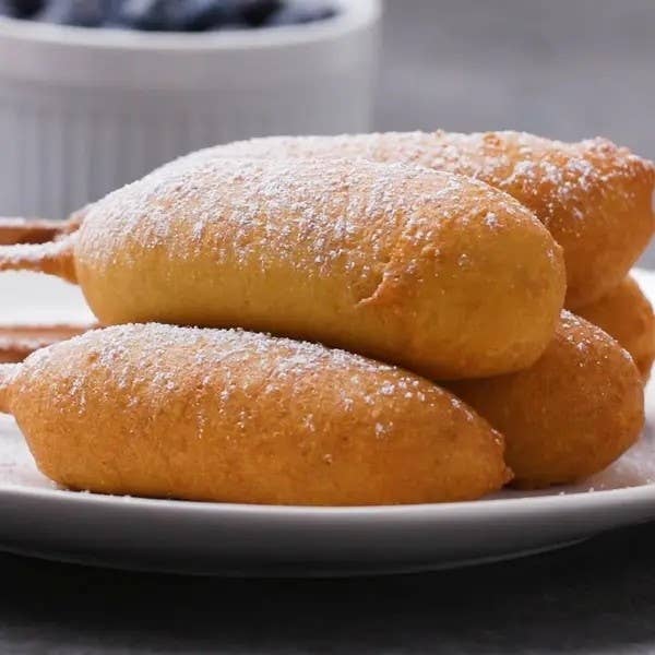 A plate of freshly fried beignets dusted with powdered sugar