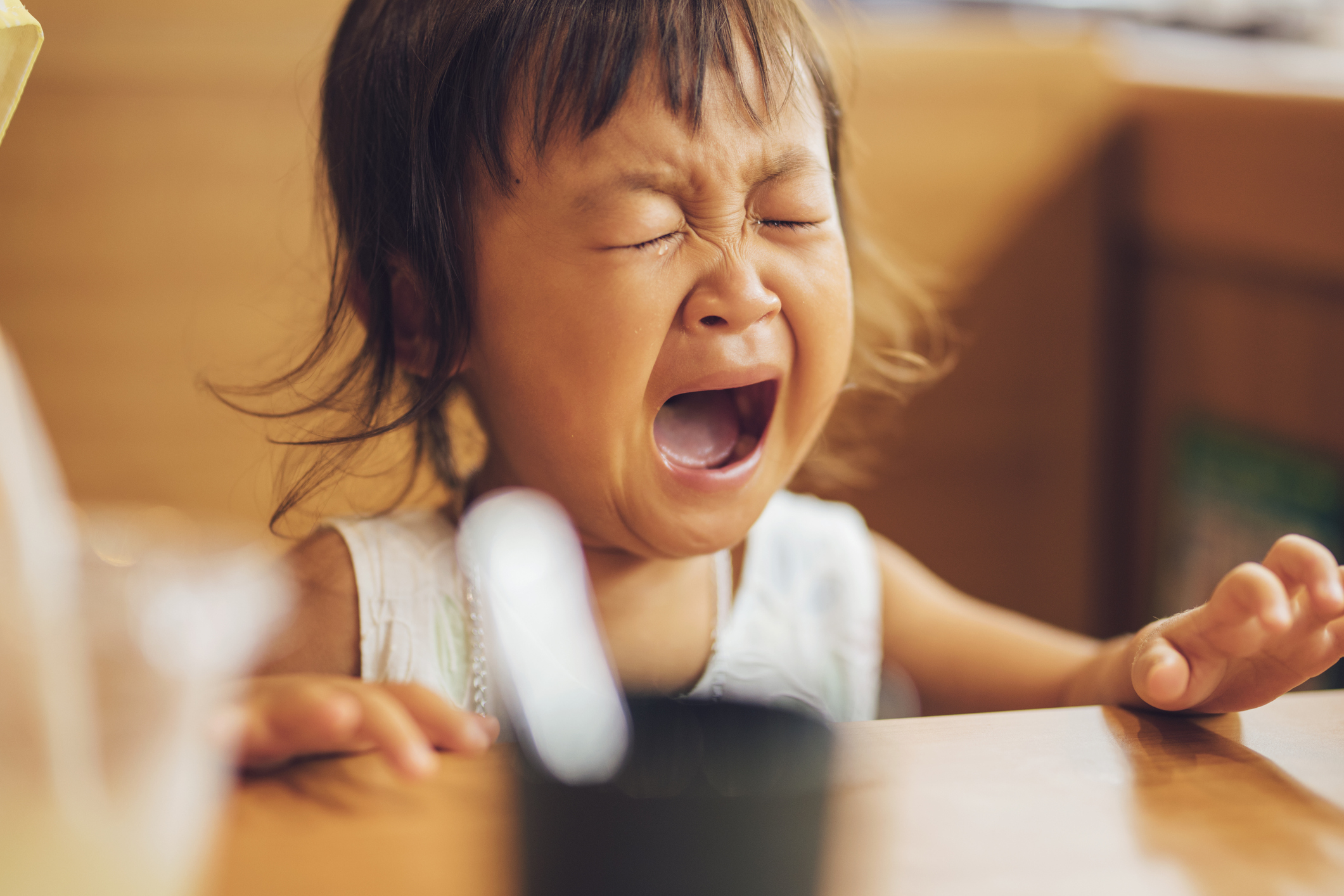 Toddler crying while sitting at a table in a restaurant