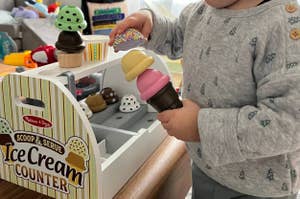 a child playing with a melissa and doug ice cream counter toy