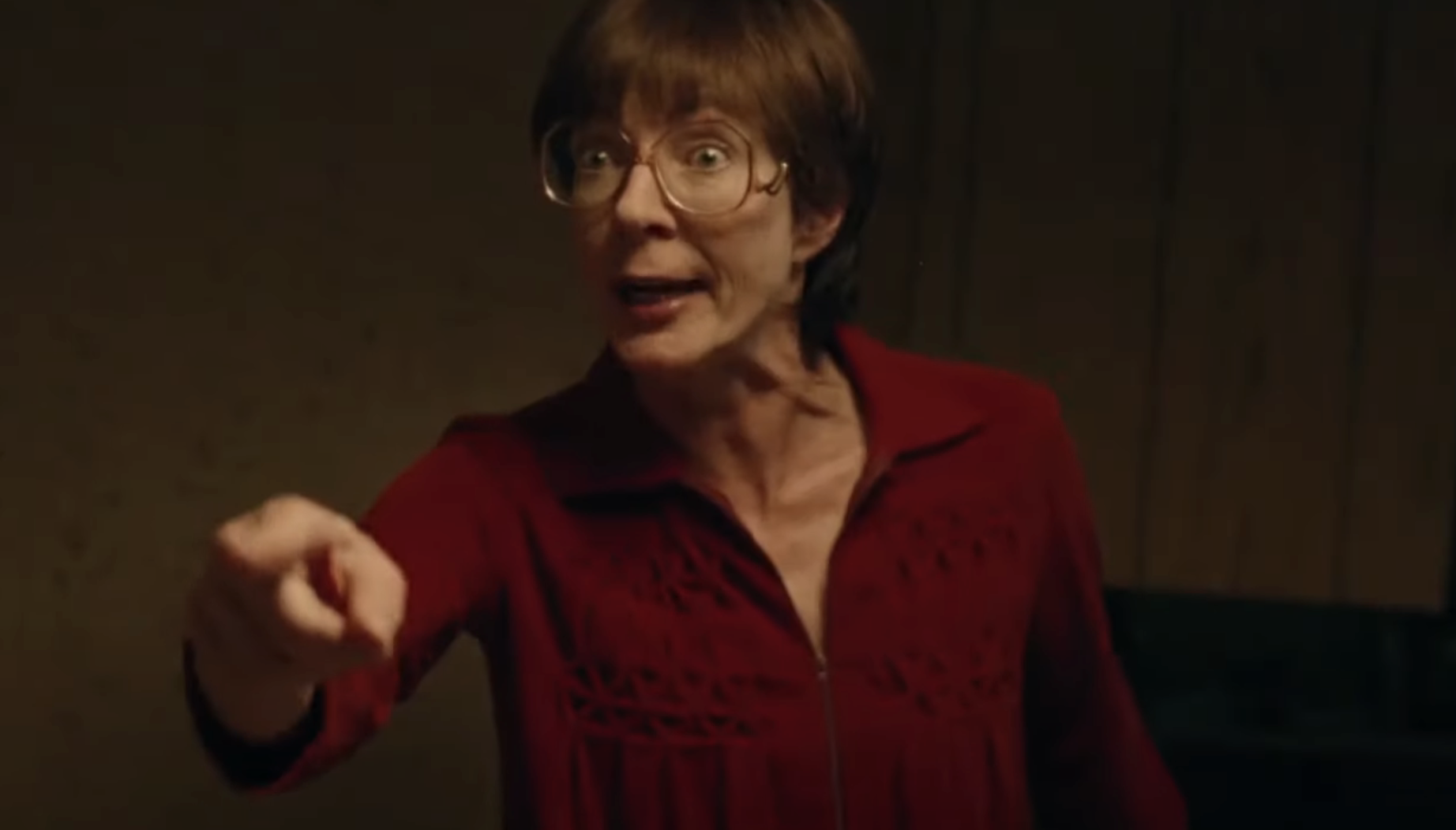 Woman in red blouse with glasses pointing, surprised expression