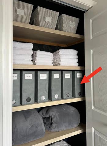 Organized closet with labeled bins and neatly stacked towels and blankets