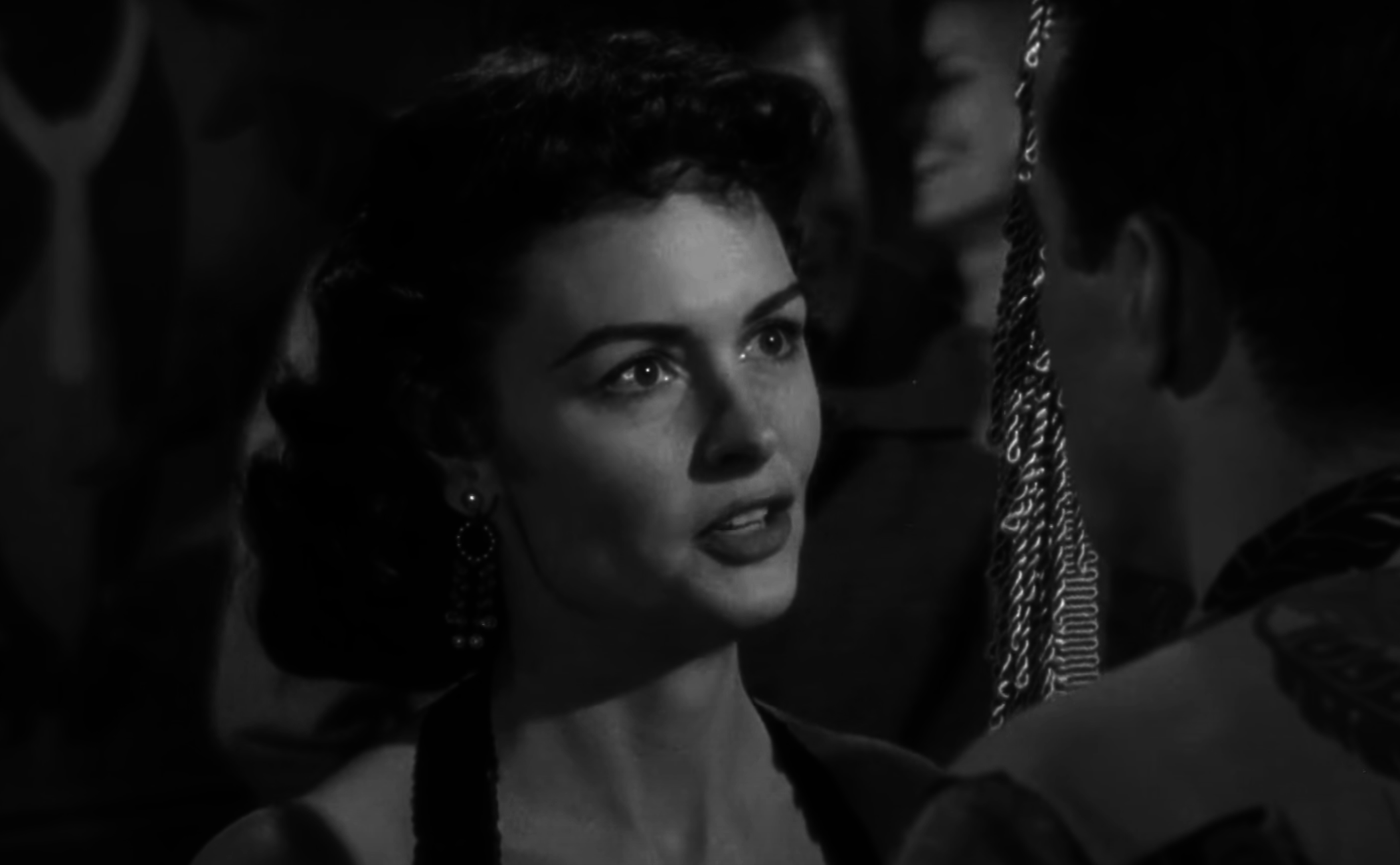 Woman in vintage attire facing a man, both looking at each other, scene from an old movie