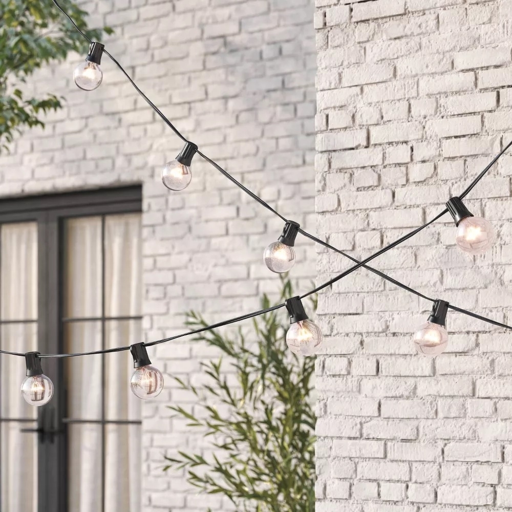 String of outdoor lights against a brick wall, suitable for patio or garden ambiance