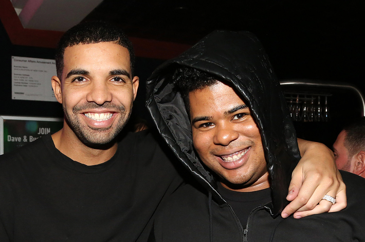 Two men smiling with their arms around each other, one wearing a black hoodie