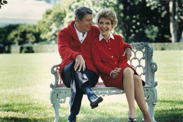 President Ronald Reagan and First Lady Nancy Reagan seated together on an ornate bench, smiling, wearing matching red jackets