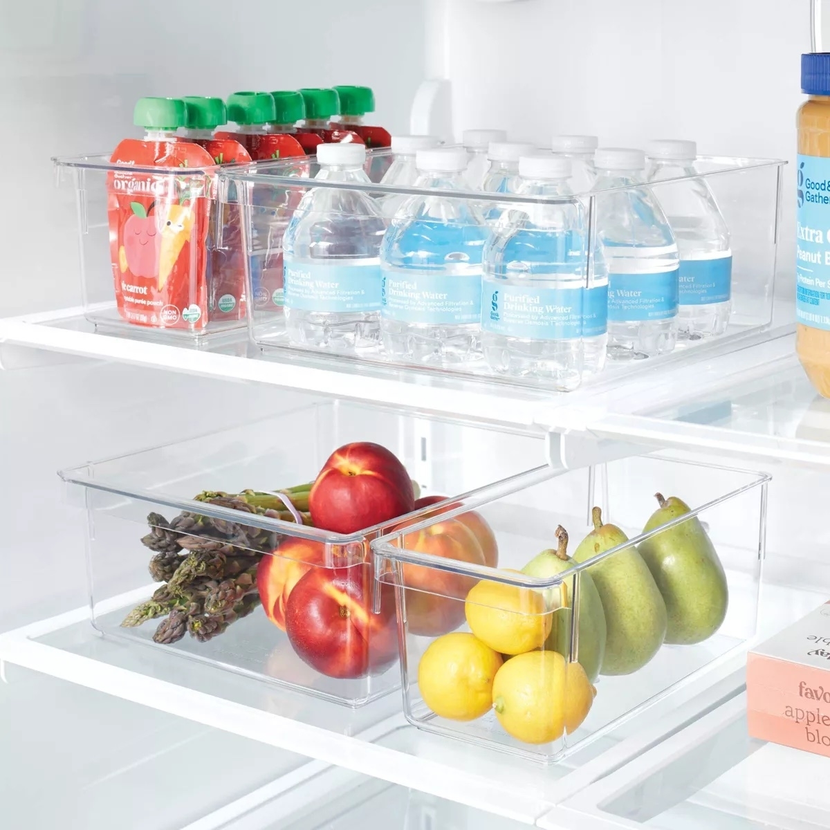 Clear fridge organizer bins containing fruit and beverages for efficient space management