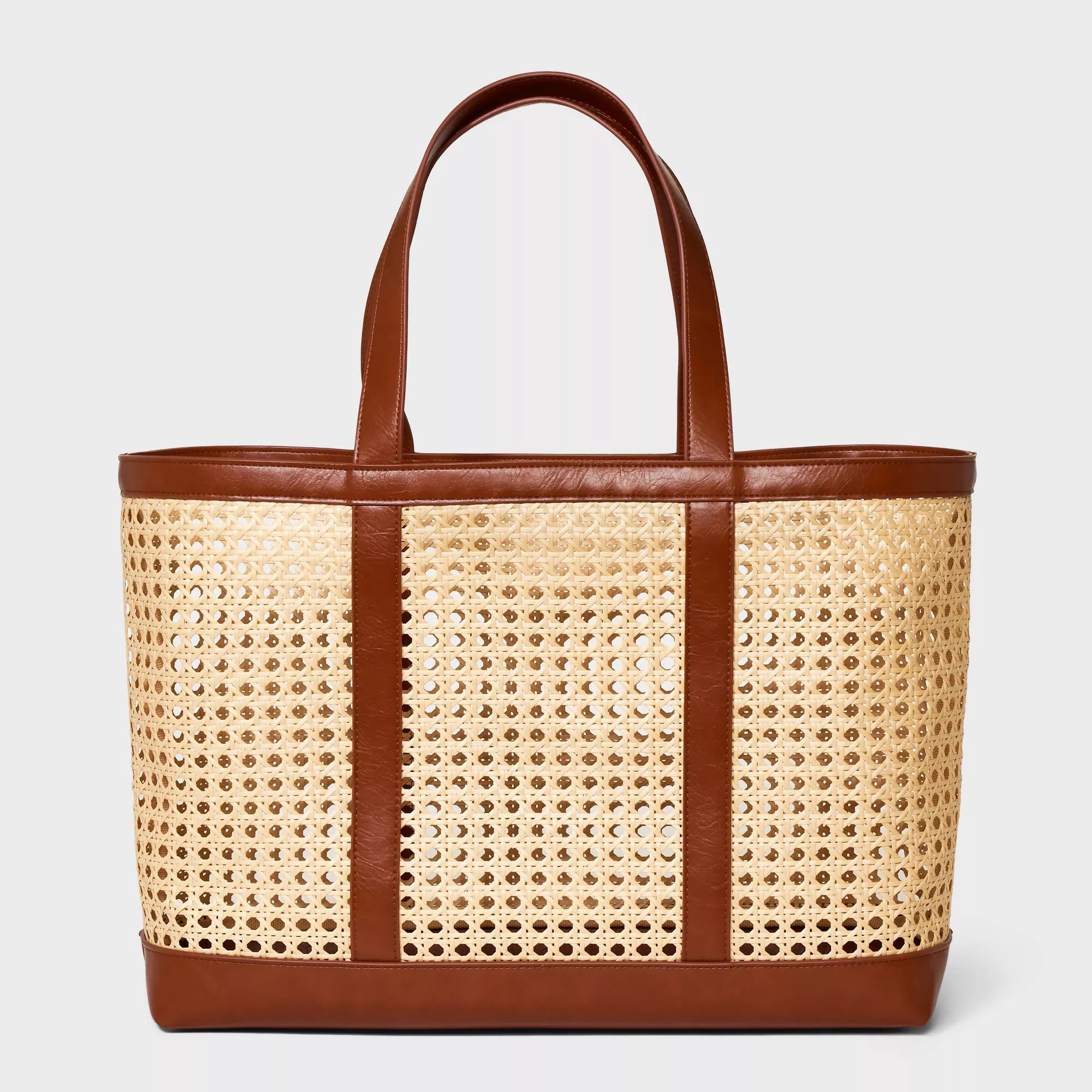 Leather-trimmed woven tote bag on a white background