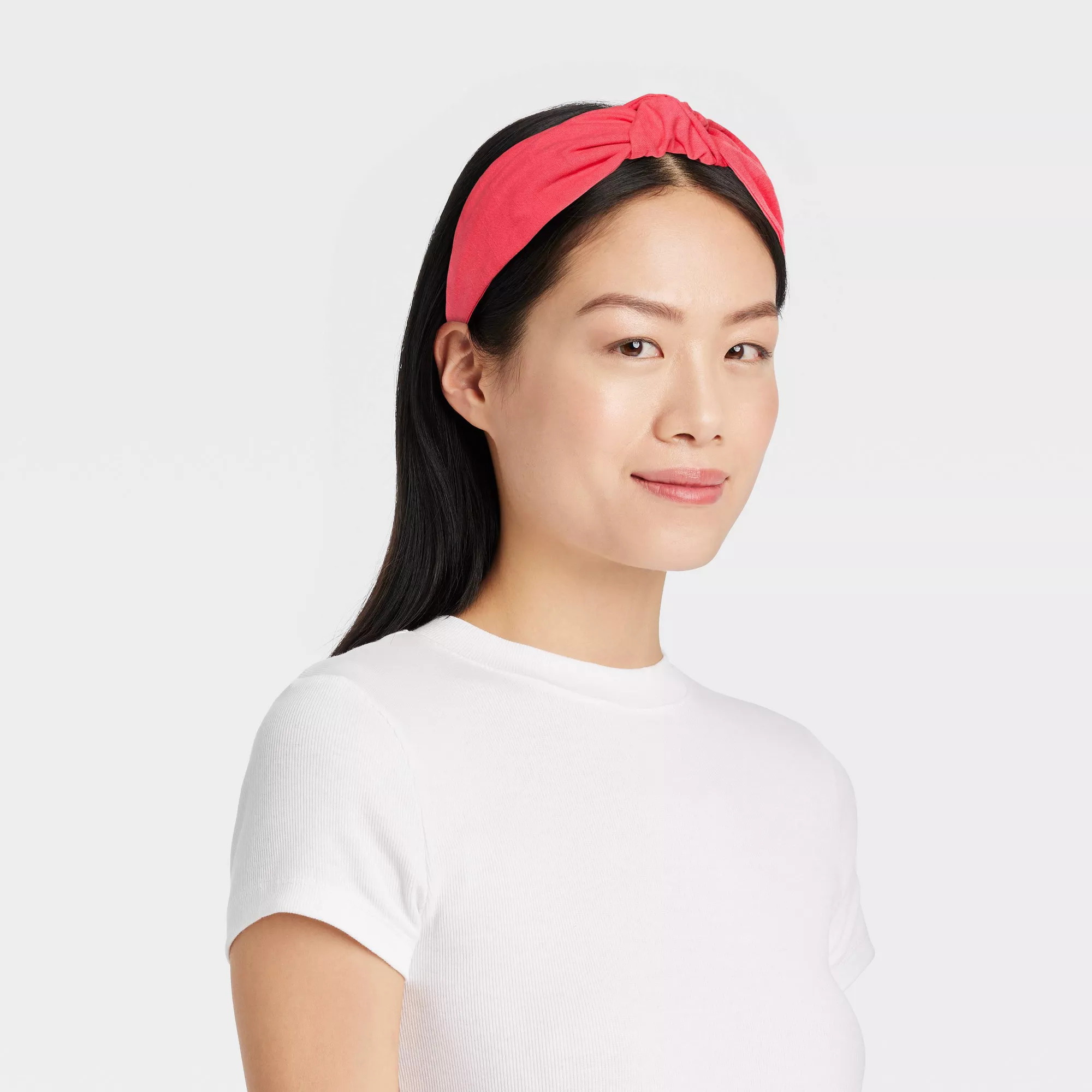 Model wearing a bright pink headband and a white T-shirt