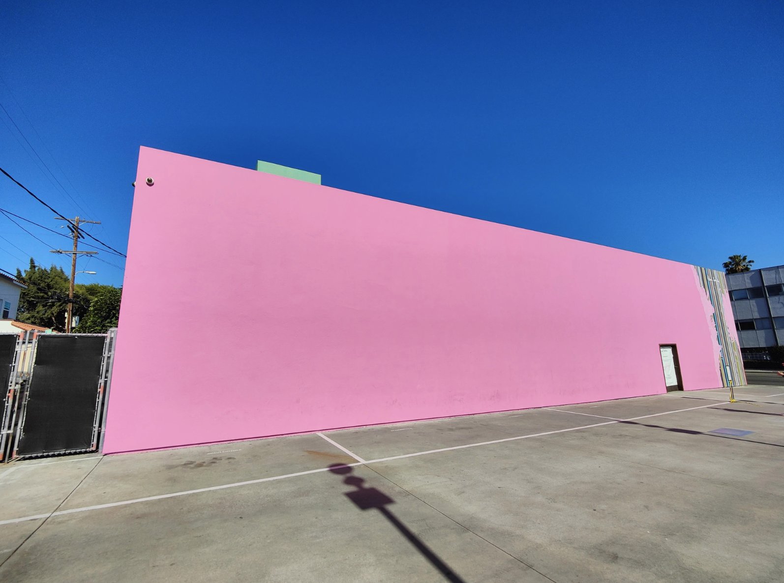 Large plain pink wall of a building with a clear blue sky, no people or text present