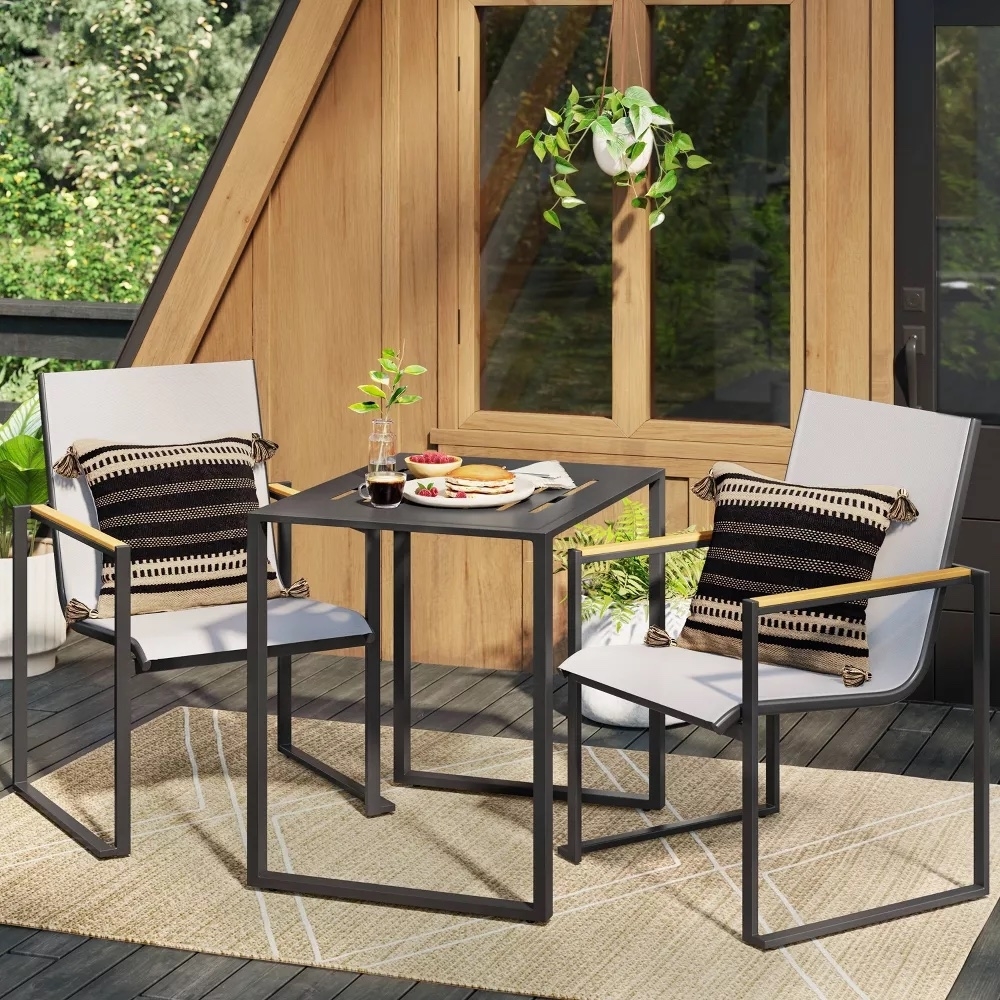 Patio furniture set with two chairs and a square table, adorned with a plant and table setting, on an outdoor deck