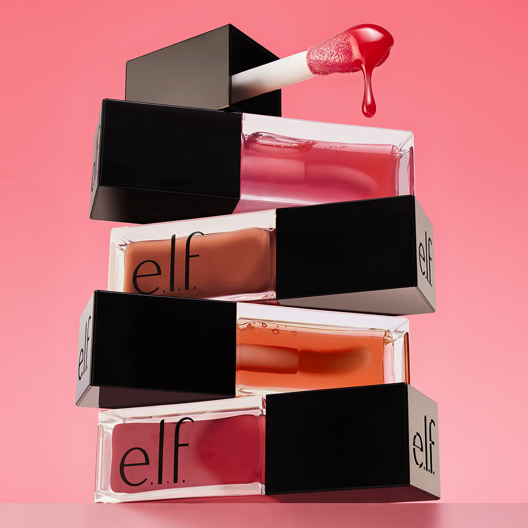A stack of e.l.f. Cosmetics lip glosses with one applicator and product hovering above