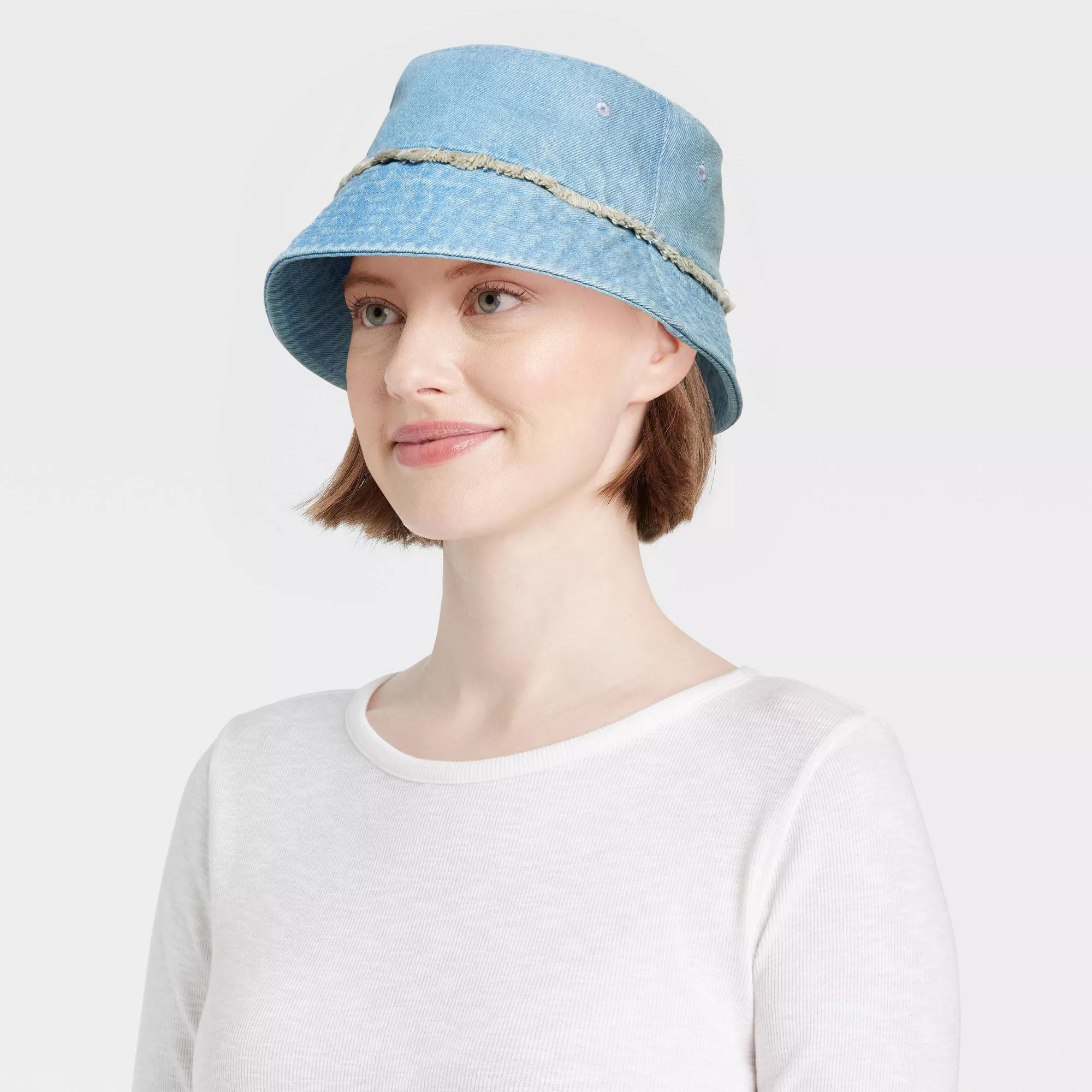 Model wearing a denim bucket hat with fringe detail