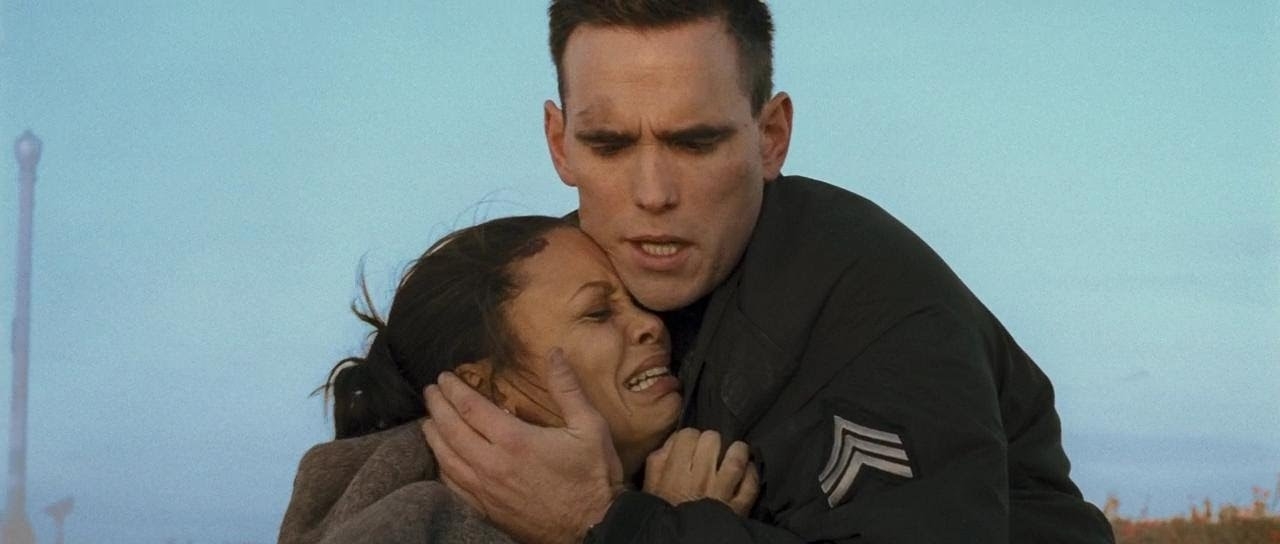 Man in a soldier&#x27;s uniform embraces a distressed woman outdoors