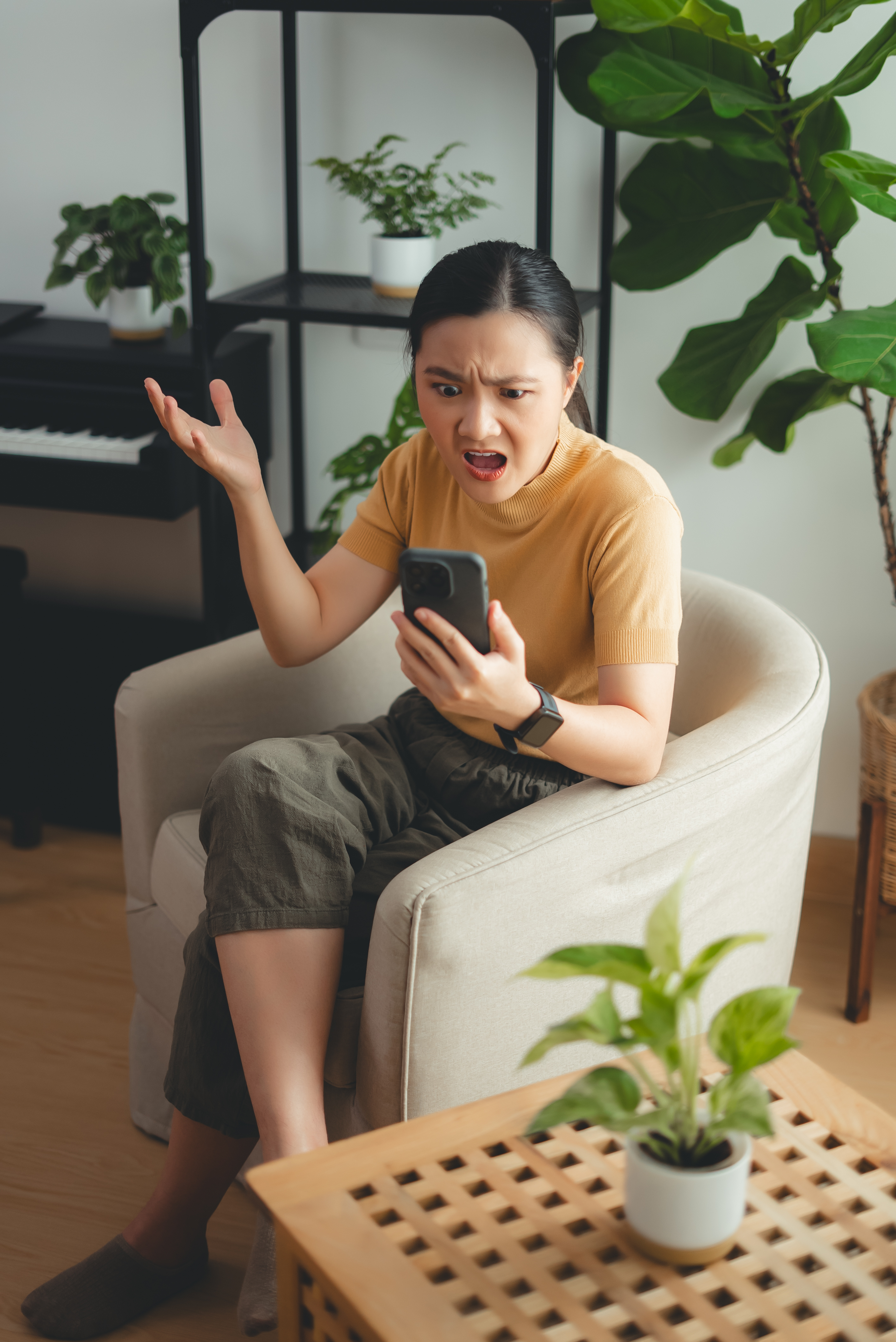 Woman looks shocked while looking at her phone in a home setting