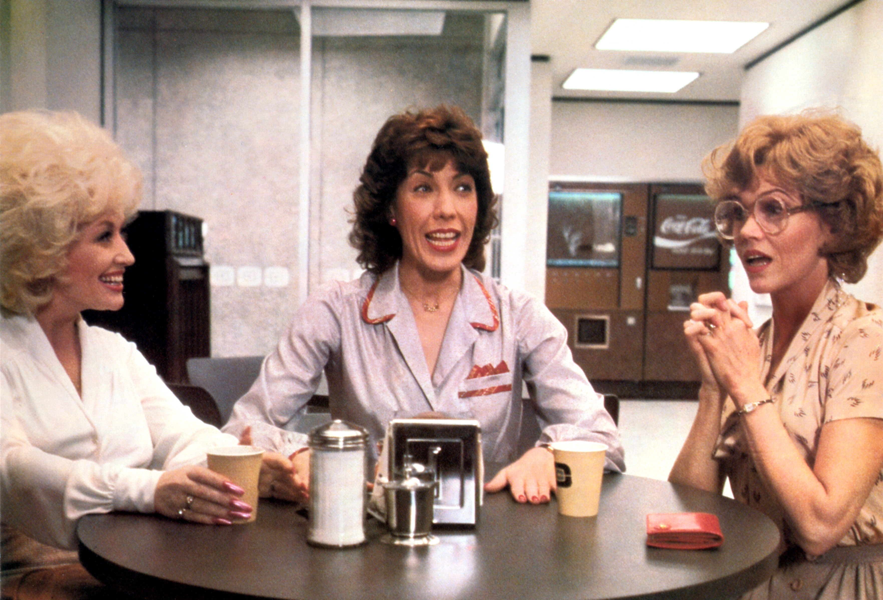 Three characters from the film &quot;9 to 5&quot; sitting at a table engaged in animated conversation