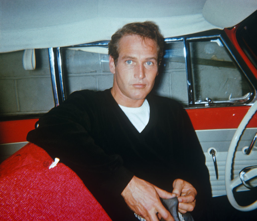Man sitting in a vintage car, looking at the camera with a focused expression