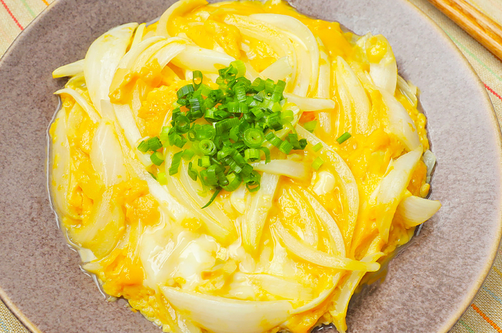 皿に盛られた玉子とじの玉ねぎとねぎが添えられた日本の料理