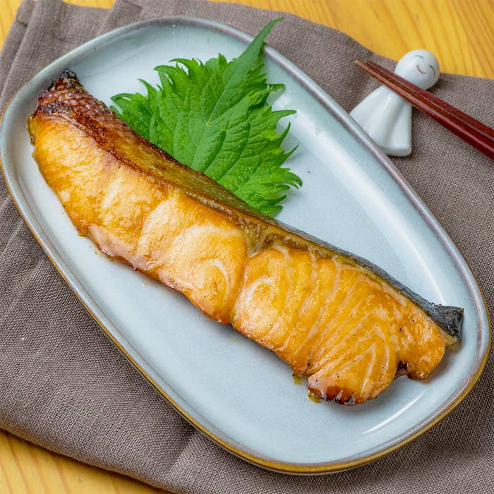 焼き魚が盛り付けられた皿と箸が載せられた食卓の写真です。