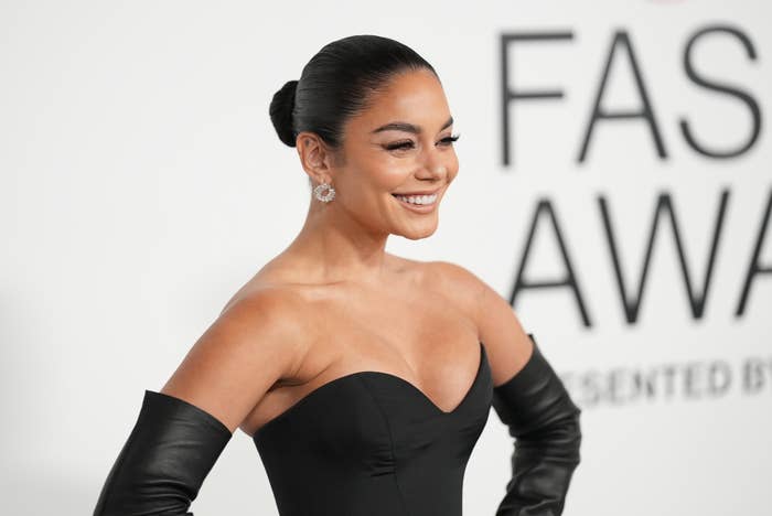 Vanessa smiling in a black off-shoulder outfit and gloves at Fashion Awards event