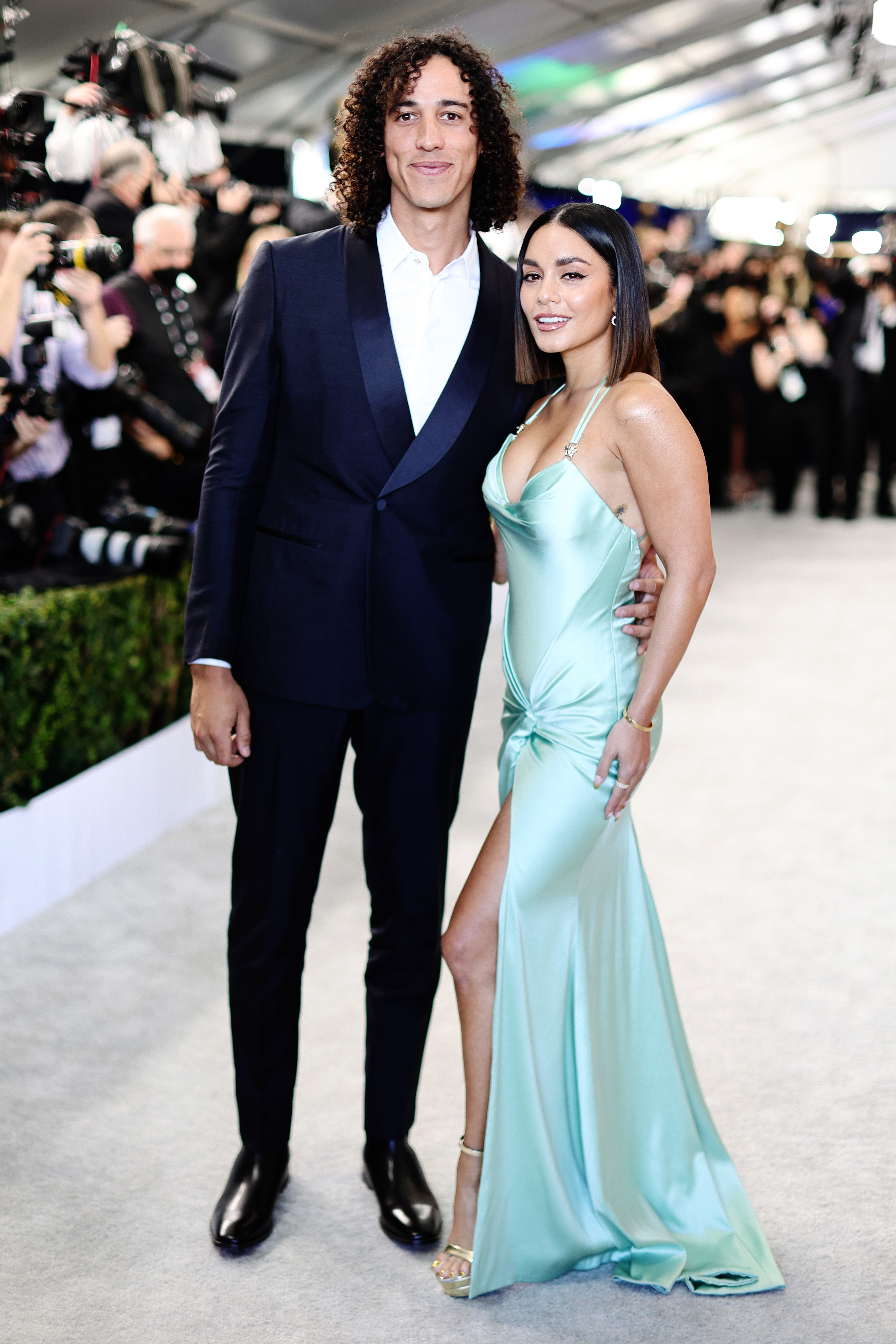 The couple posing together on the red carpet: Cole in a classic suit and Vanessa in a satin gown with a thigh-high slit