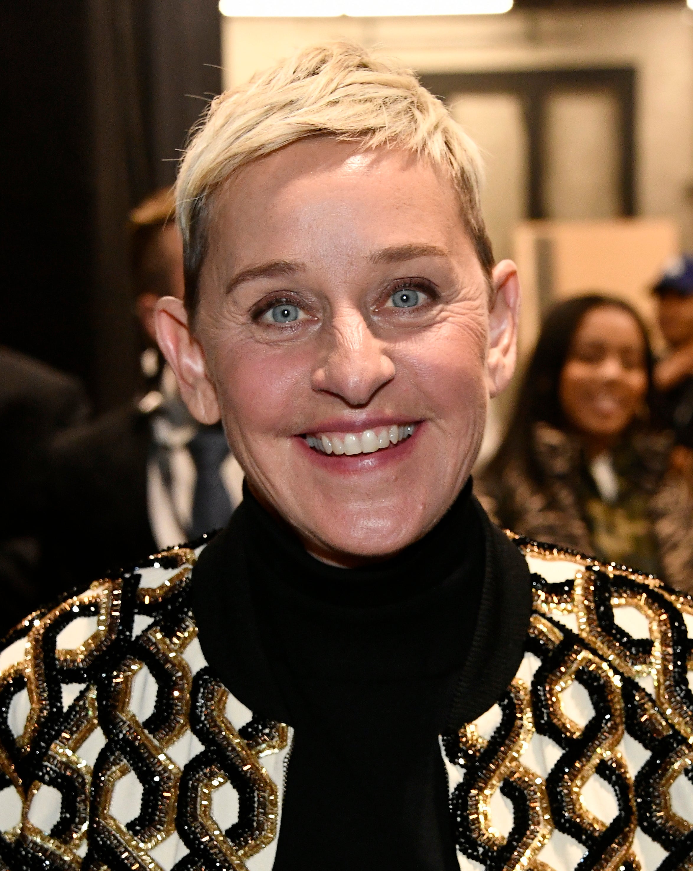 Ellen DeGeneres smiling in a black turtleneck and a beaded jacket