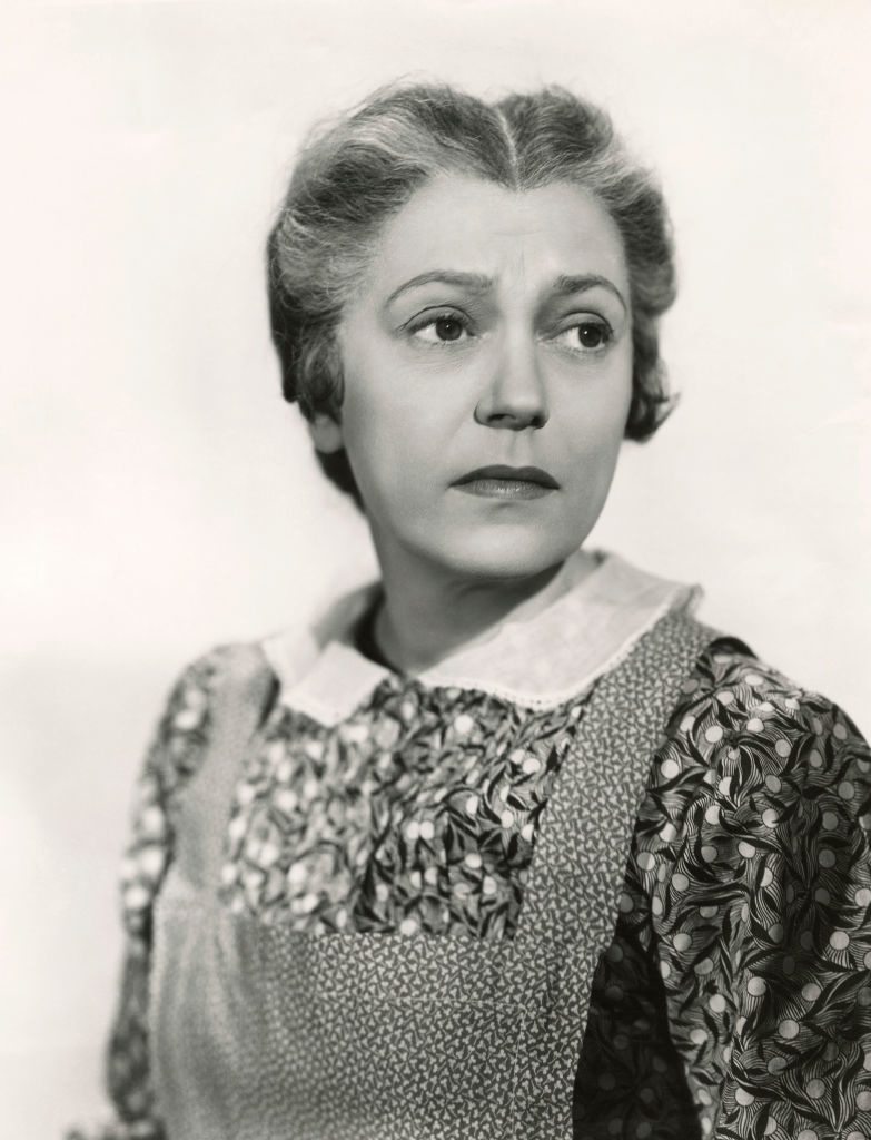 Vintage black and white still of Alice wearing a period costume with a collared dress
