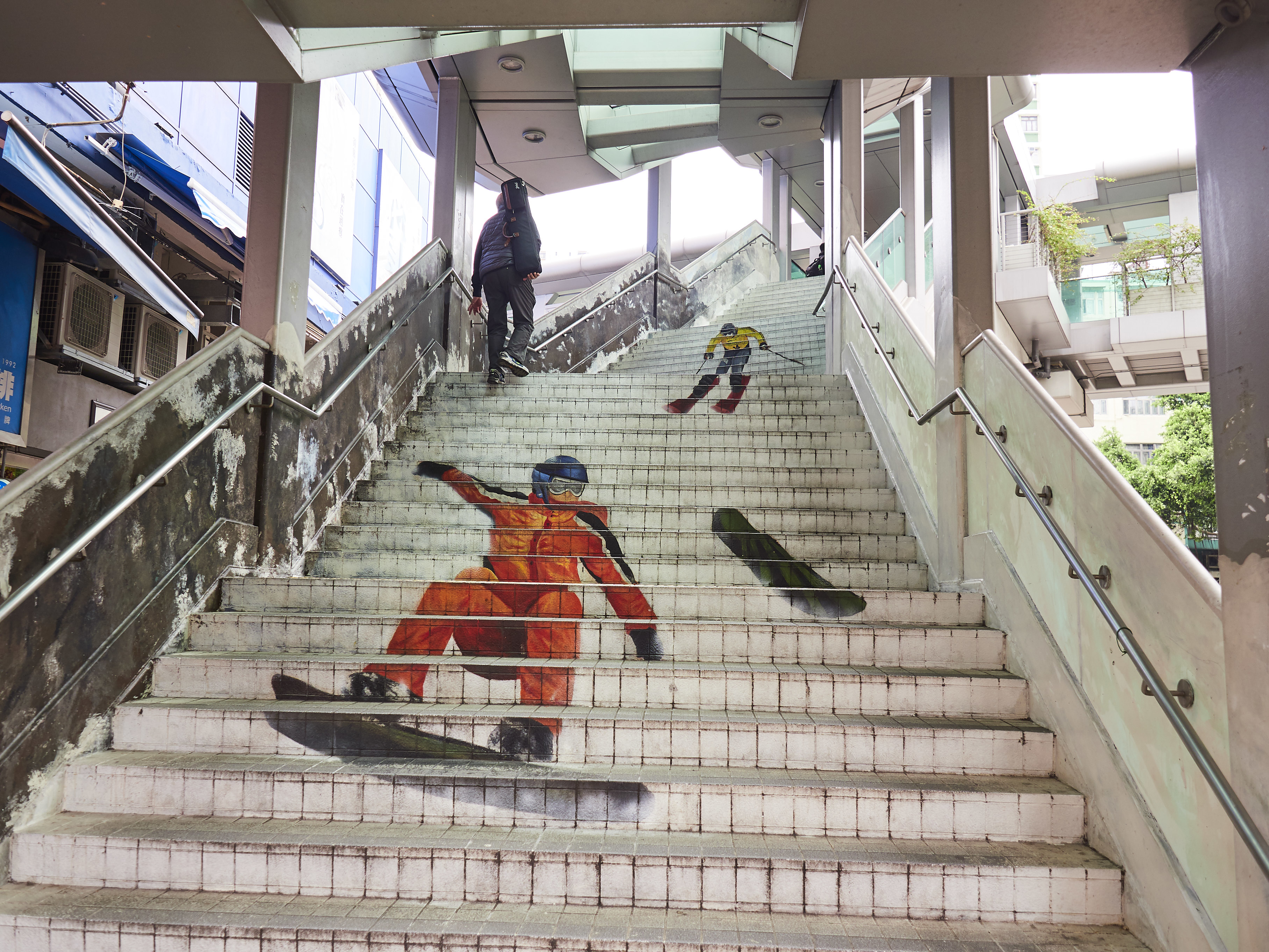 Street art of a skier painted on outdoor stairs with people ascending