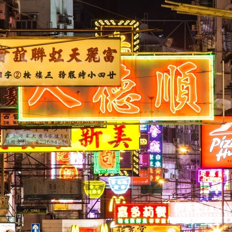 Neon signs with Chinese characters illuminate a bustling city street at night